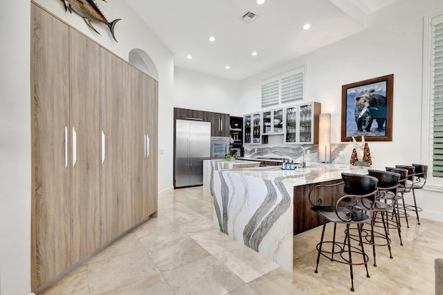 kitchen featuring light stone countertops, visible vents, a peninsula, stainless steel appliances, and modern cabinets