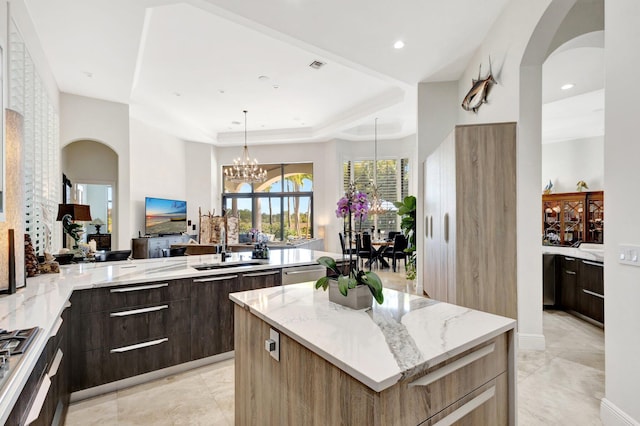 kitchen with a center island, light stone countertops, arched walkways, modern cabinets, and a sink