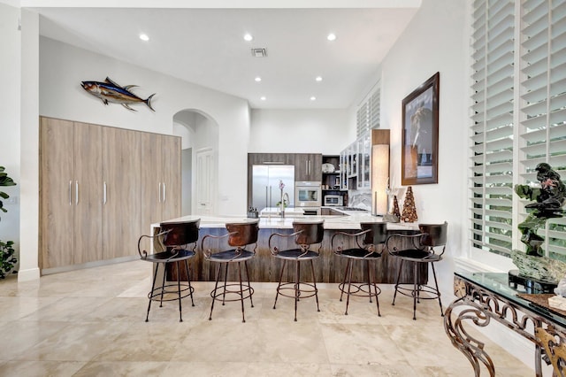 kitchen with oven, visible vents, modern cabinets, built in fridge, and a peninsula