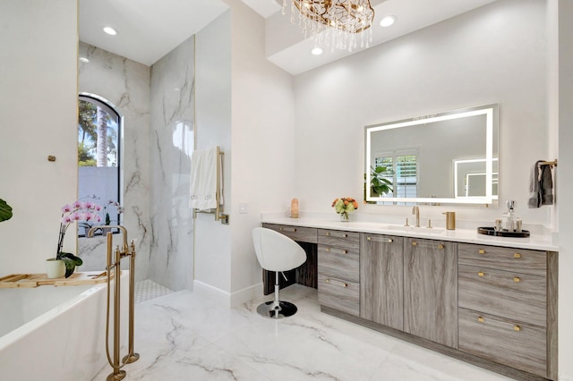 full bathroom with a notable chandelier, marble finish floor, recessed lighting, a freestanding bath, and vanity