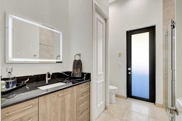 bathroom with tile patterned floors, an enclosed shower, toilet, and vanity