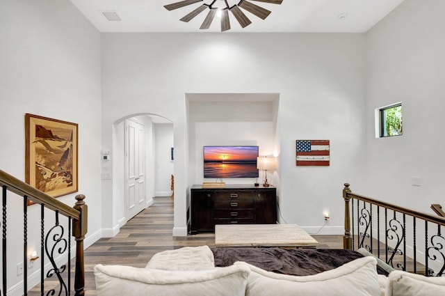 living room with baseboards, arched walkways, wood finished floors, and a ceiling fan