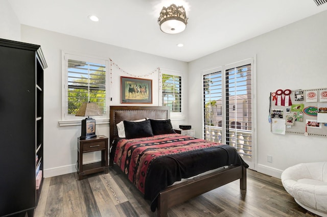 bedroom with baseboards, multiple windows, and dark wood-type flooring