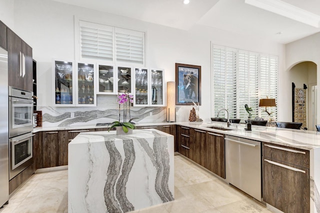 kitchen featuring dark brown cabinets, appliances with stainless steel finishes, modern cabinets, and glass insert cabinets