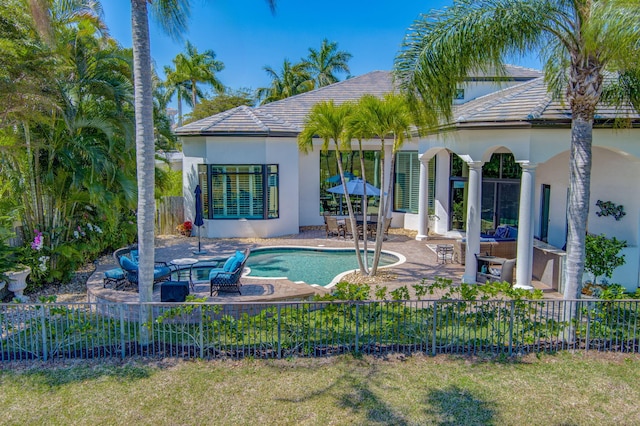 rear view of property featuring a patio area, stucco siding, a tile roof, and a fenced backyard