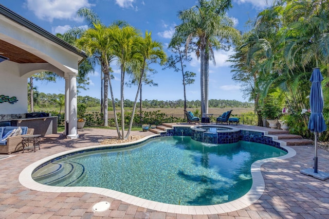 view of pool with a patio, a pool with connected hot tub, outdoor dry bar, and fence