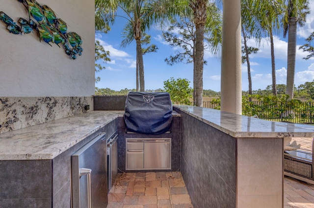 view of patio featuring an outdoor kitchen, outdoor wet bar, fence, and a grill