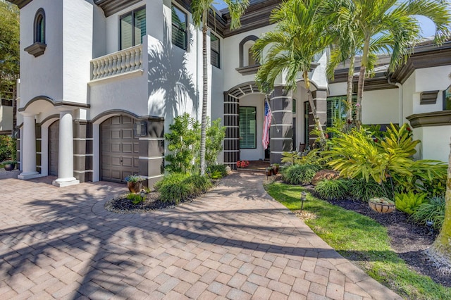 doorway to property with stucco siding, decorative driveway, and an attached garage