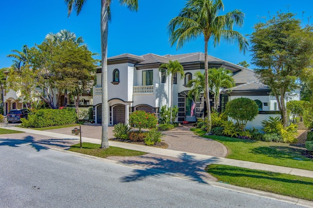 mediterranean / spanish home featuring a tiled roof, decorative driveway, and stucco siding