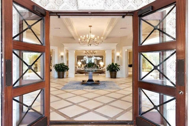 entryway featuring a notable chandelier, beamed ceiling, a healthy amount of sunlight, and ornate columns