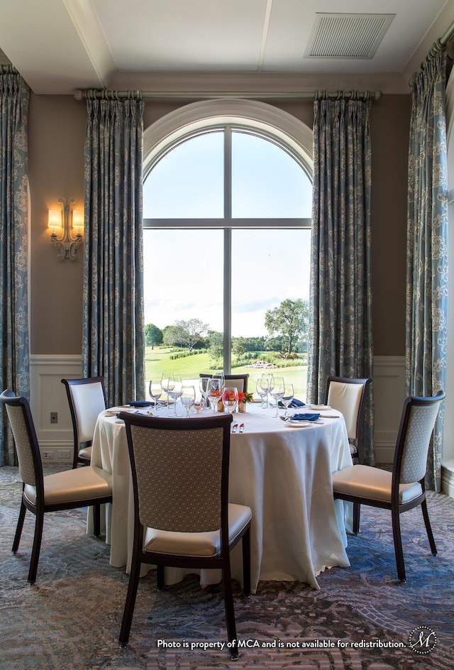 dining room featuring a decorative wall, visible vents, and wainscoting