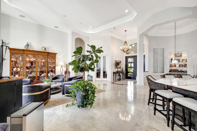 living room with visible vents, a tray ceiling, a towering ceiling, arched walkways, and a notable chandelier