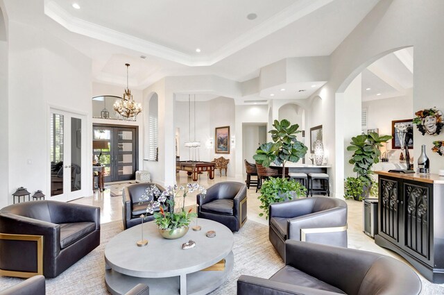 living area with a tray ceiling, arched walkways, an inviting chandelier, and crown molding