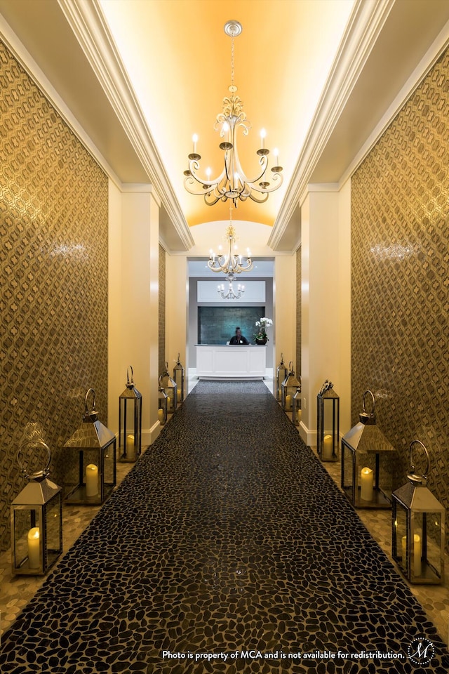 hallway with vaulted ceiling, ornamental molding, and a chandelier