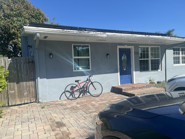 bungalow-style home featuring stucco siding and fence