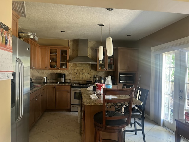 kitchen featuring decorative backsplash, stainless steel appliances, wall chimney exhaust hood, dark stone countertops, and glass insert cabinets