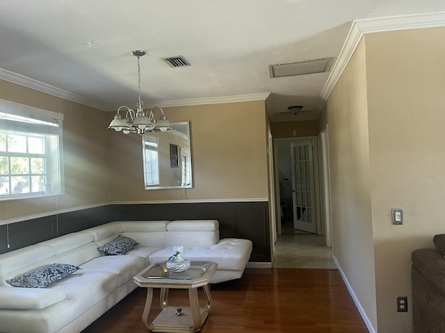 living room with a textured ceiling, ornamental molding, wood finished floors, and a chandelier