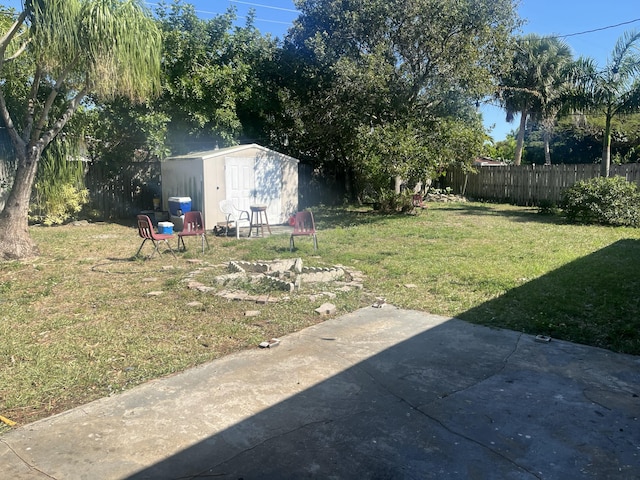 view of yard with an outbuilding, a fenced backyard, a storage shed, and a patio area