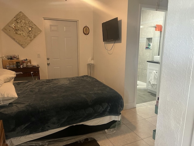 bedroom with light tile patterned floors, radiator heating unit, and connected bathroom