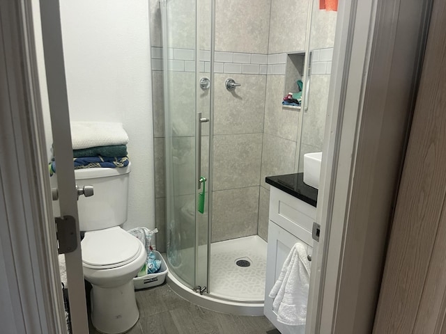 full bath featuring toilet, a stall shower, and vanity