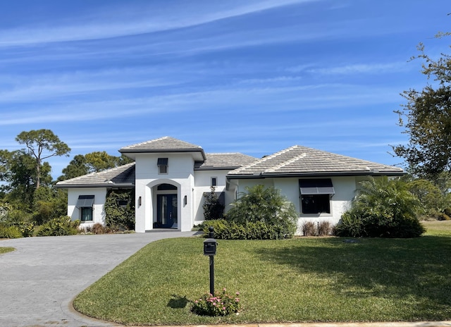 prairie-style home featuring stucco siding, concrete driveway, and a front lawn