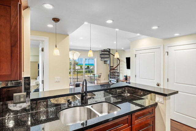 kitchen featuring a sink, recessed lighting, dark stone countertops, and hanging light fixtures