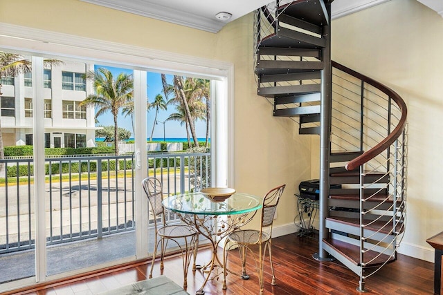 dining space with baseboards, wood finished floors, ornamental molding, and stairs