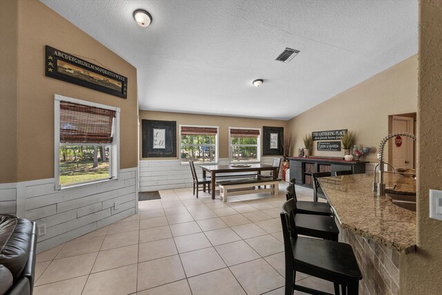 living room with light tile patterned floors, visible vents, a ceiling fan, and lofted ceiling