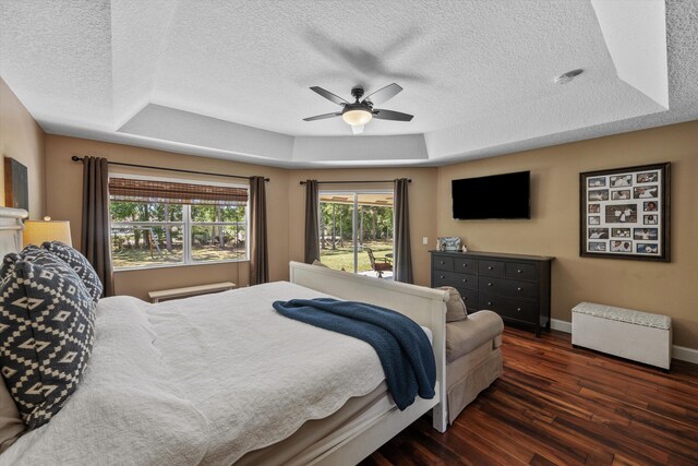 bedroom with dark wood-style flooring, access to exterior, baseboards, and a raised ceiling