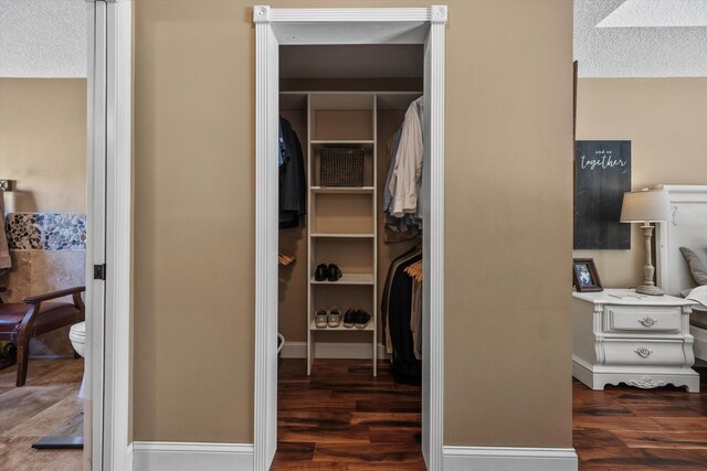 walk in closet with dark wood-type flooring