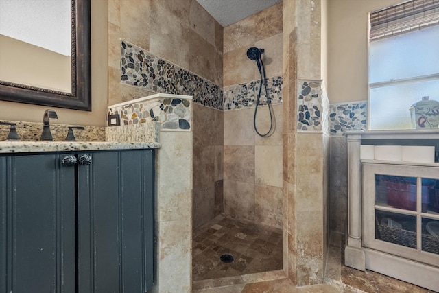 bathroom with tiled shower and vanity