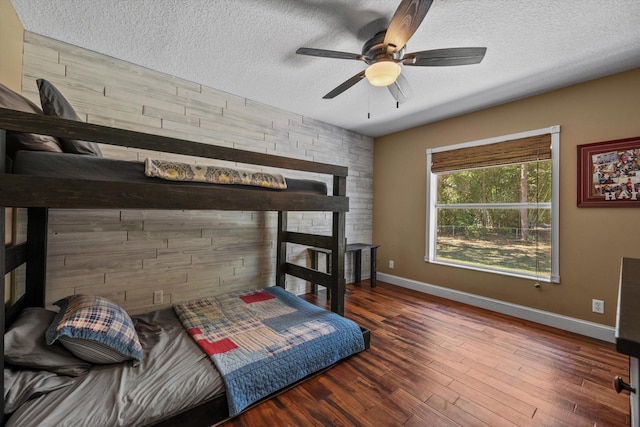 bedroom featuring ceiling fan, wood finished floors, baseboards, and a textured ceiling