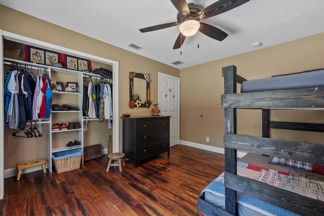 bedroom with wood finished floors, baseboards, visible vents, a closet, and a textured ceiling