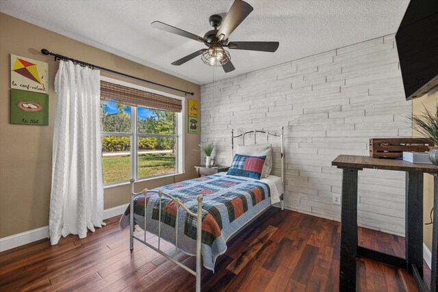bedroom with baseboards, a textured ceiling, visible vents, ceiling fan, and wood finished floors