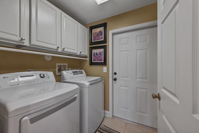 washroom with light tile patterned flooring, cabinet space, a textured ceiling, and separate washer and dryer