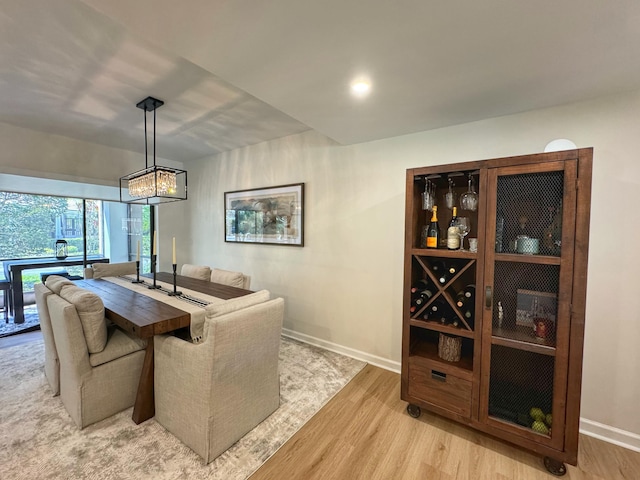 dining space featuring baseboards, a chandelier, and light wood finished floors