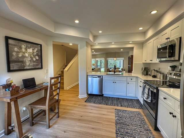 kitchen featuring light wood-type flooring, a sink, stainless steel appliances, white cabinets, and light countertops