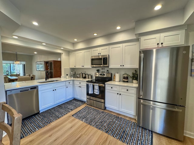 kitchen featuring wood finished floors, recessed lighting, a sink, stainless steel appliances, and light countertops