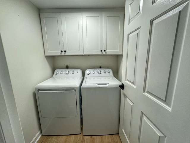 laundry area with washer and dryer, baseboards, cabinet space, and light wood-style floors