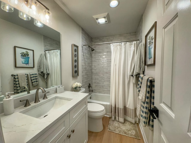 full bathroom featuring toilet, wood finished floors, vanity, and shower / bath combination with curtain