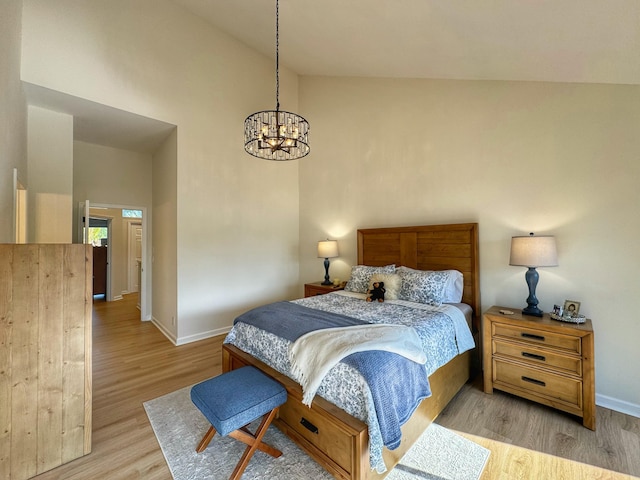 bedroom with baseboards, a notable chandelier, wood finished floors, and high vaulted ceiling