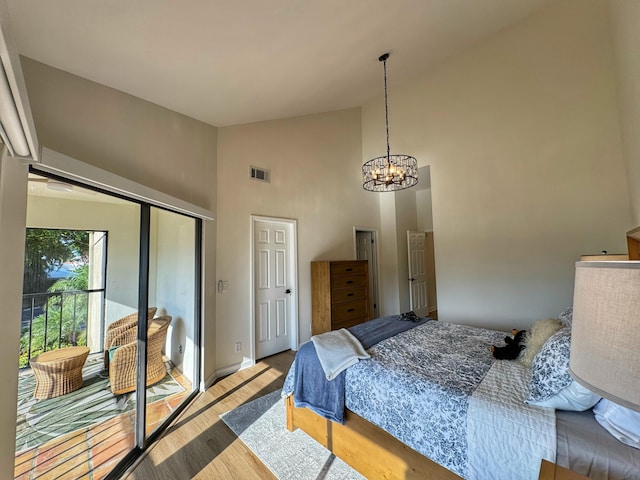 bedroom featuring high vaulted ceiling, wood finished floors, visible vents, and a chandelier