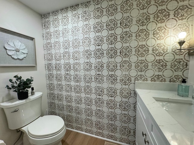 bathroom with toilet, wood finished floors, and vanity