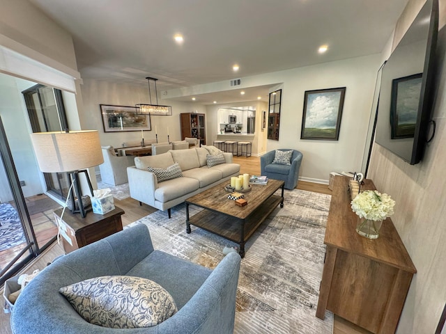 living room with recessed lighting, visible vents, baseboards, and wood finished floors