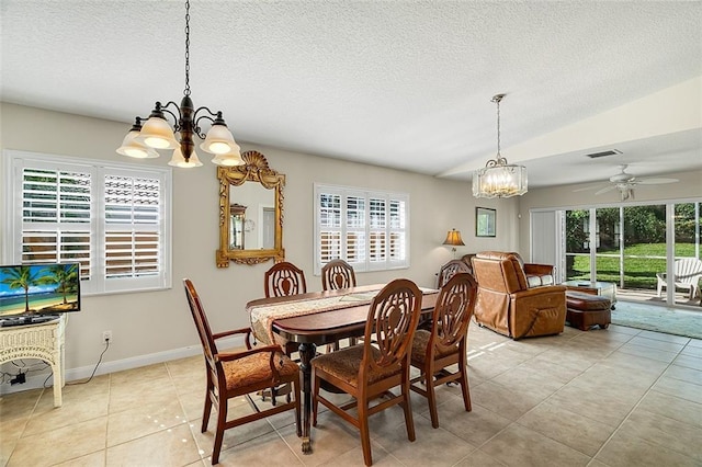 dining room featuring lofted ceiling, ceiling fan with notable chandelier, visible vents, and a textured ceiling