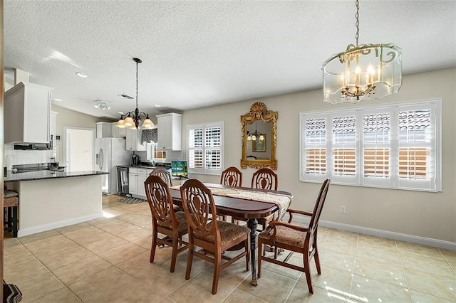 dining area with lofted ceiling, a textured ceiling, light tile patterned flooring, baseboards, and a chandelier