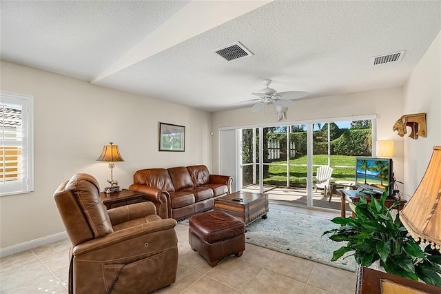 living area featuring visible vents, baseboards, a textured ceiling, and ceiling fan