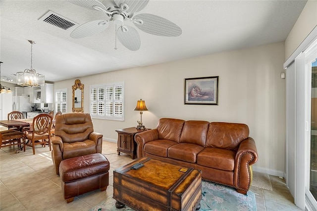 living room featuring visible vents, ceiling fan with notable chandelier, and baseboards