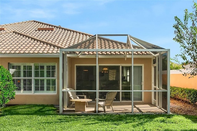 rear view of property with stucco siding, a patio, a lanai, and a tile roof