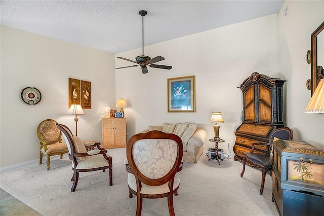 sitting room with a textured ceiling, carpet flooring, baseboards, and ceiling fan